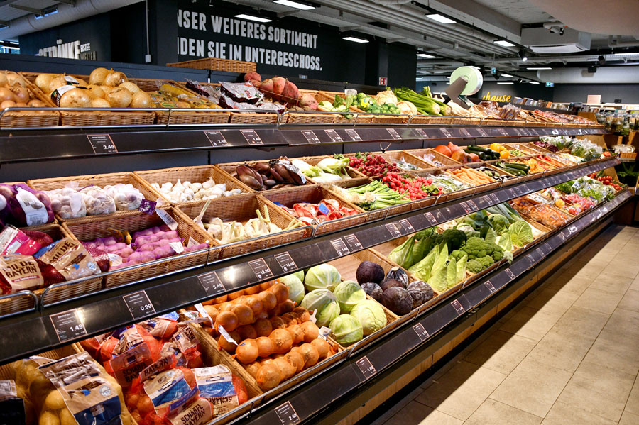 Großes Gemüse- und Obstregal mit Körben und Preisschildern.