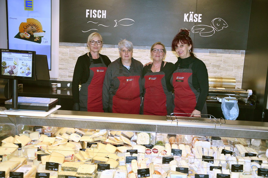 Team an der Frischetheke steht hinter Käse- und Fischtheke und lächelt in die Kamera.